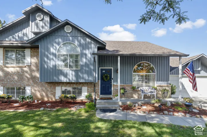 Multi-level residence featuring a brand new shingle roof and brand new vertical siding, arched windows, fully landscaped with mature trees