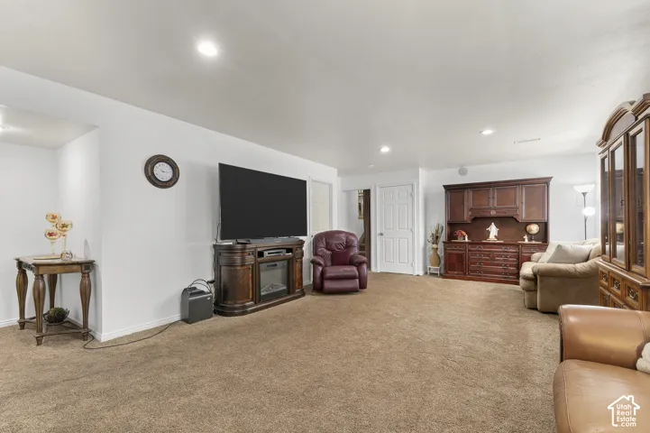 Spacious room with light brown carpeting, white walls, and recessed lighting