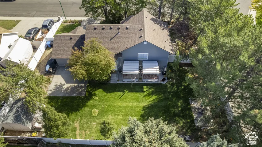Expansive green lawn, mature trees, multi-level home, deck structure, and brand new shingle roofing