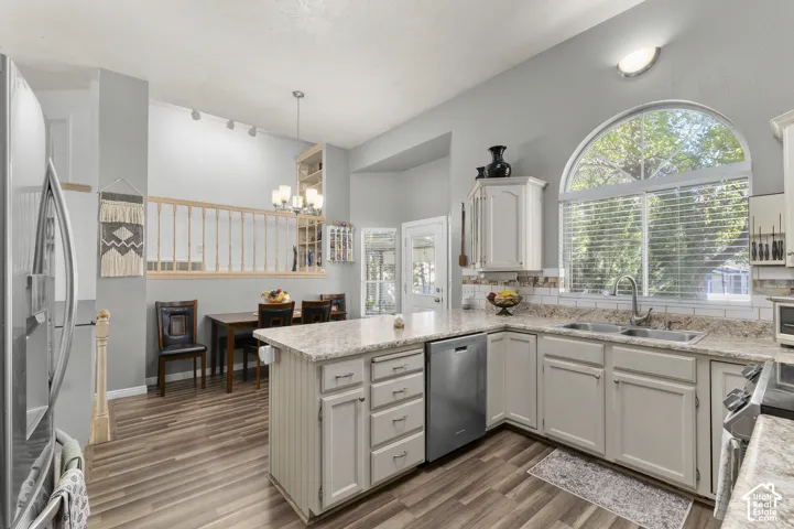 Kitchen featuring wood-finish flooring, light cabinetry, subway tile backsplash, and an arched window