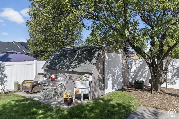 Concrete patio area, detached storage shed, new white privacy fencing, mature tree, and green lawn