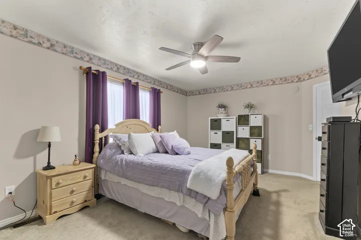 Master room, carpeted flooring, ceiling fan with integrated lighting, wall-mounted television, and a white interior door