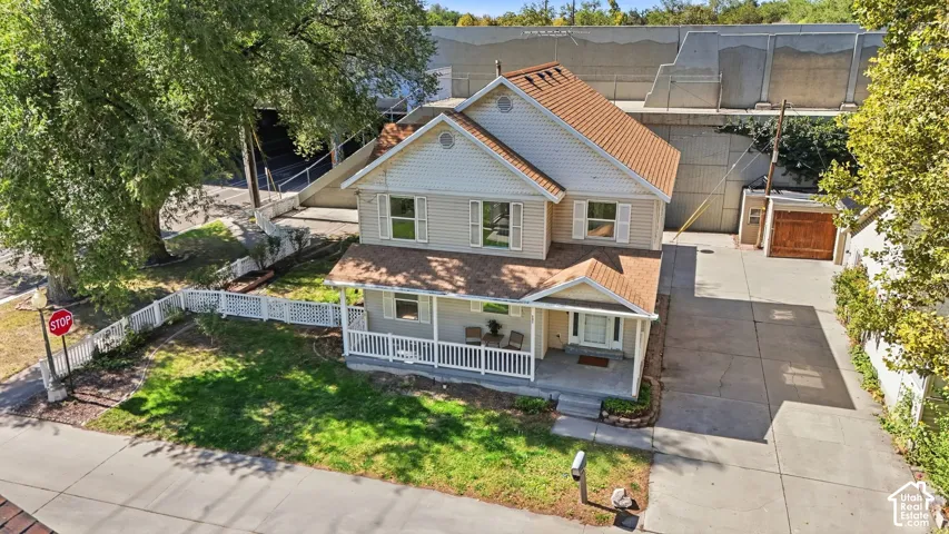 Two-story residence with a covered front porch, white picket fence, and extensive concrete driveway