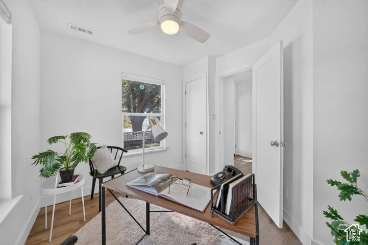 Recessed window, ceiling fan with integrated lighting, wood-finish flooring, white doors, and painted walls