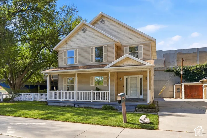 Two-story residence with a covered porch, white picket fence, and a concrete driveway