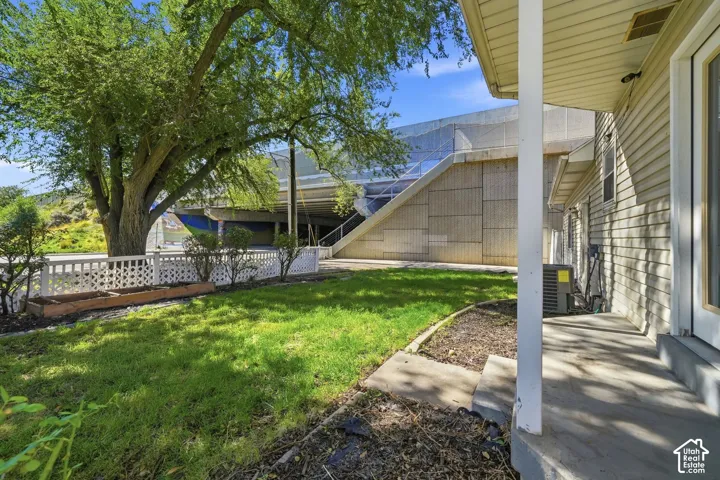 Side yard featuring mature tree, white lattice fencing, and planted beds
