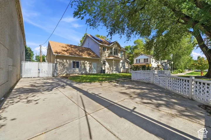 Concrete driveway with a detached garage, white lattice fencing, and mature trees