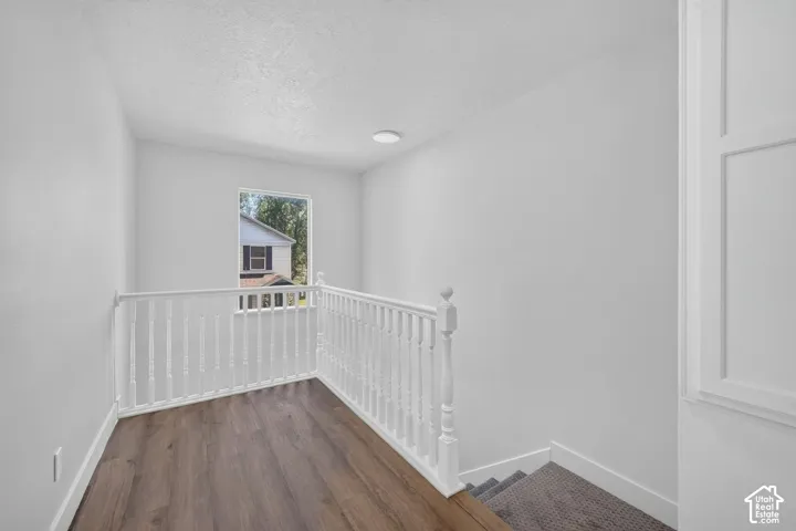 Wood-finish flooring, white spindle railing, and a window with natural light