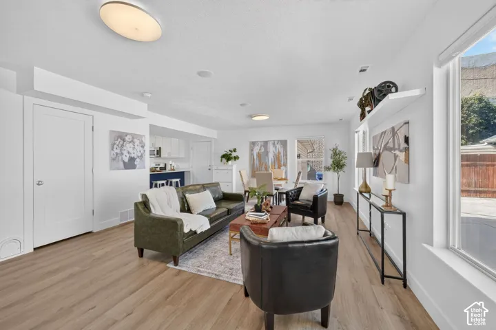 Open-concept living area with wood-finish flooring, white walls, and recessed lighting