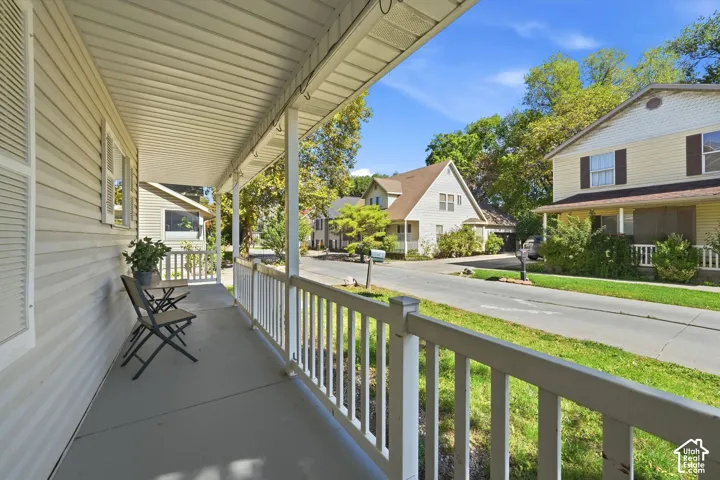Covered front porch with white railings, textured siding, and multiple windows