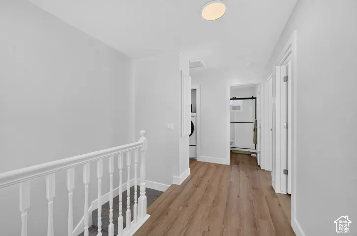 Wood-finish flooring throughout, white painted railing, and a modern ceiling light fixture