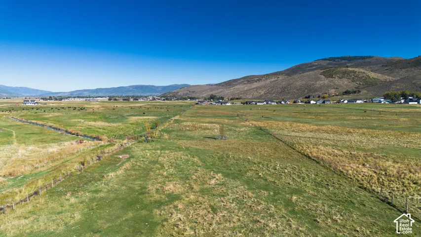 Expansive rural acreage featuring a natural water channel, distant mountain ranges, and residential structures