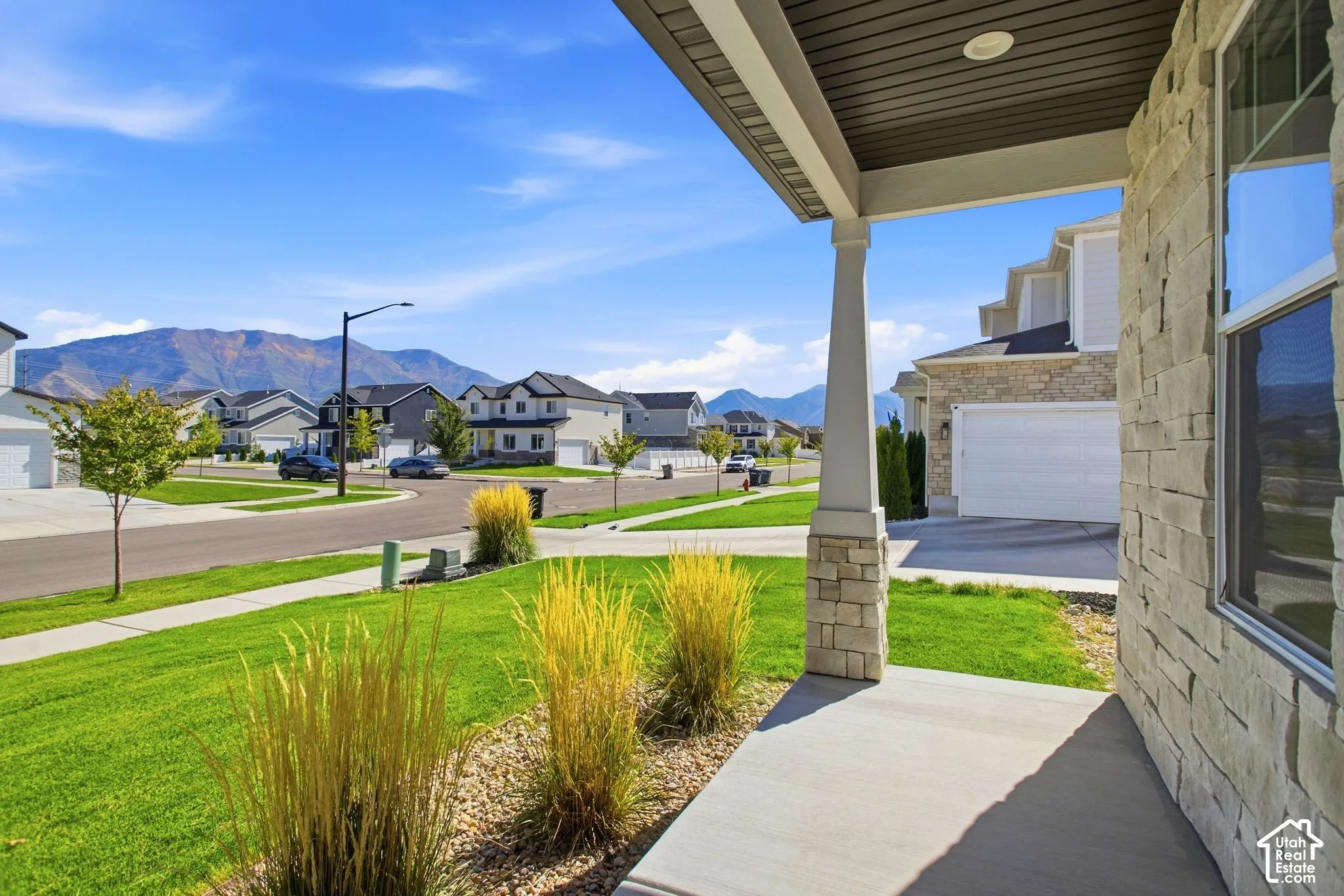 Stone veneer exterior with a covered porch, featuring a concrete walkway and decorative columns