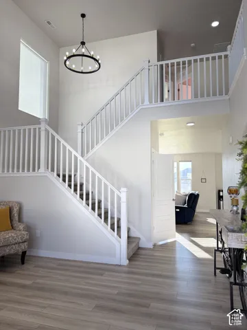 Two-story foyer with wood-finish flooring, white spindle banister, and a black circular chandelier