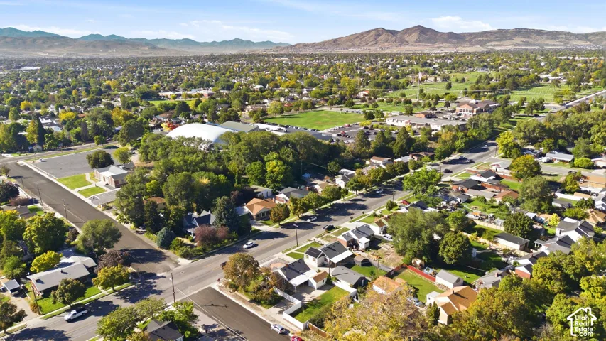Expansive neighborhood featuring mature trees, numerous residential structures, and distant mountains