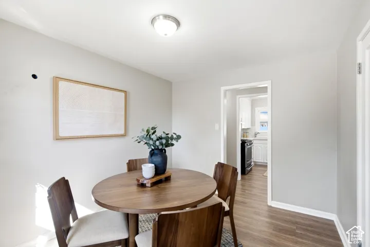 Recessed ceiling light fixture, neutral wall color, wood-finish flooring, white trim details, open doorway to kitchen