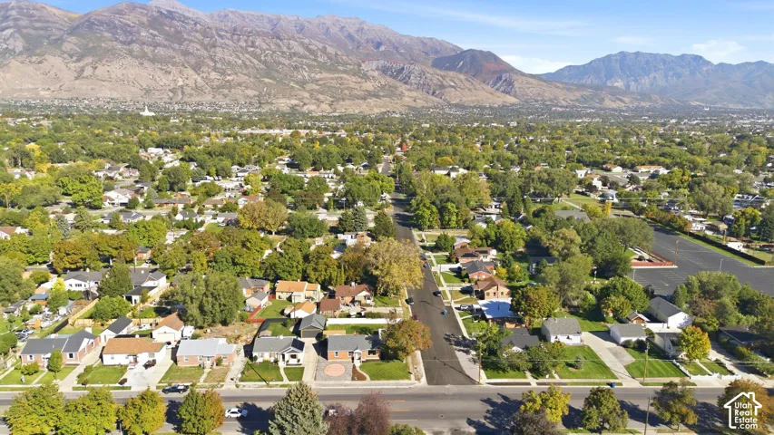 Residential neighborhood with mature trees, established landscaping, and mountain backdrop