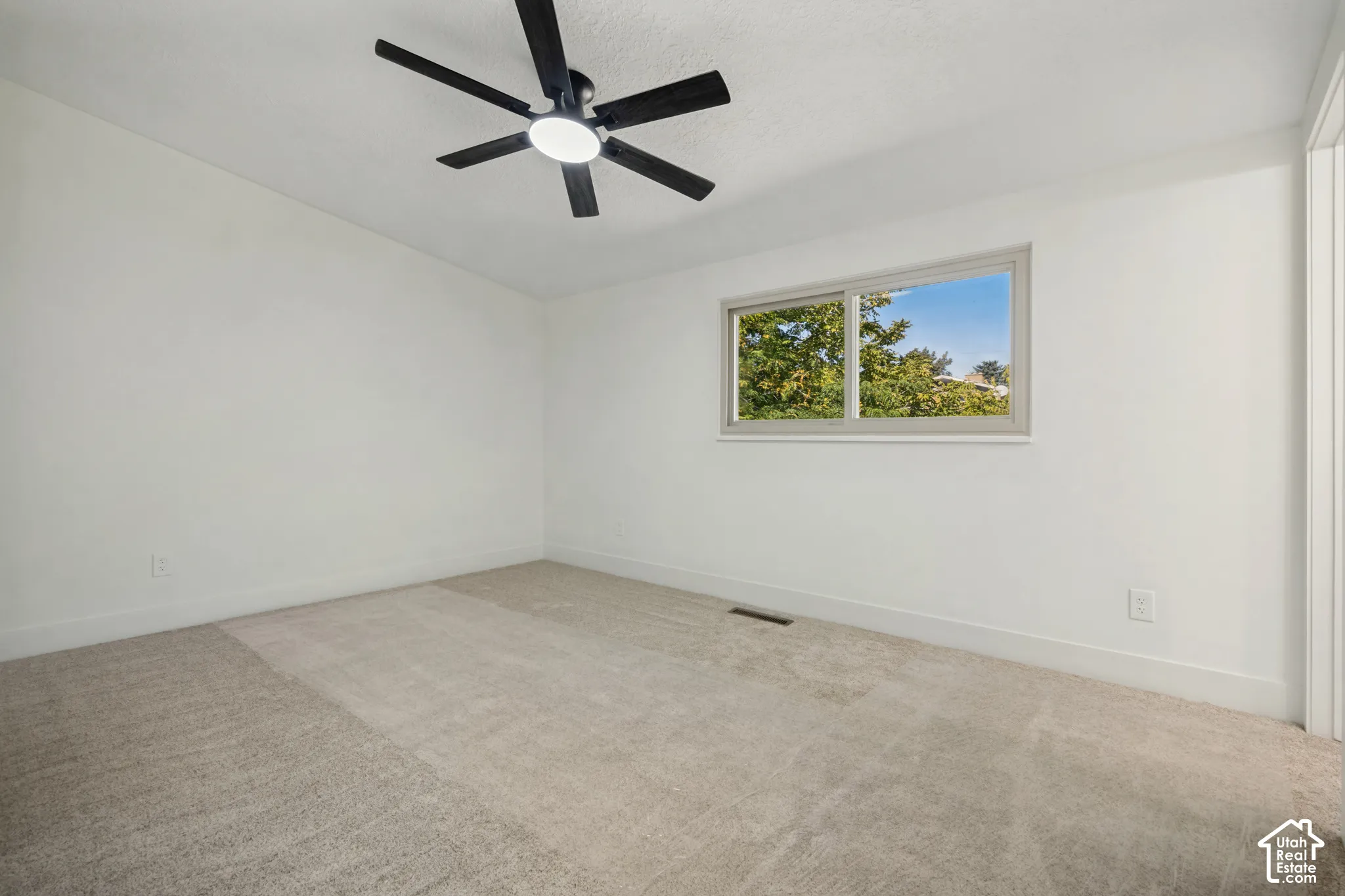 Recessed window with natural light, integrated ceiling fan with lighting, and neutral carpeting