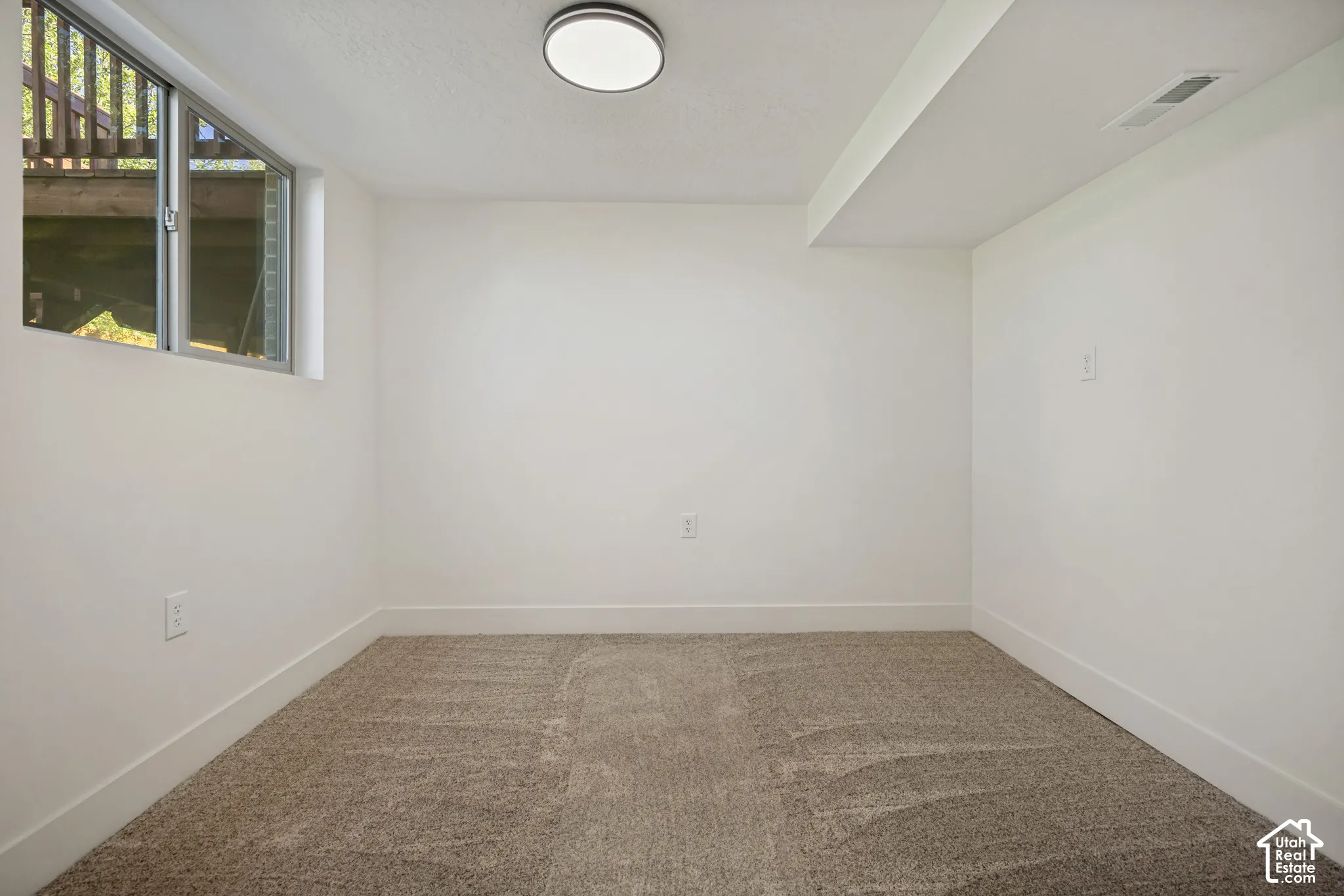 Recessed window, neutral wall paint, flush-mount ceiling light, carpeting, and white baseboards
