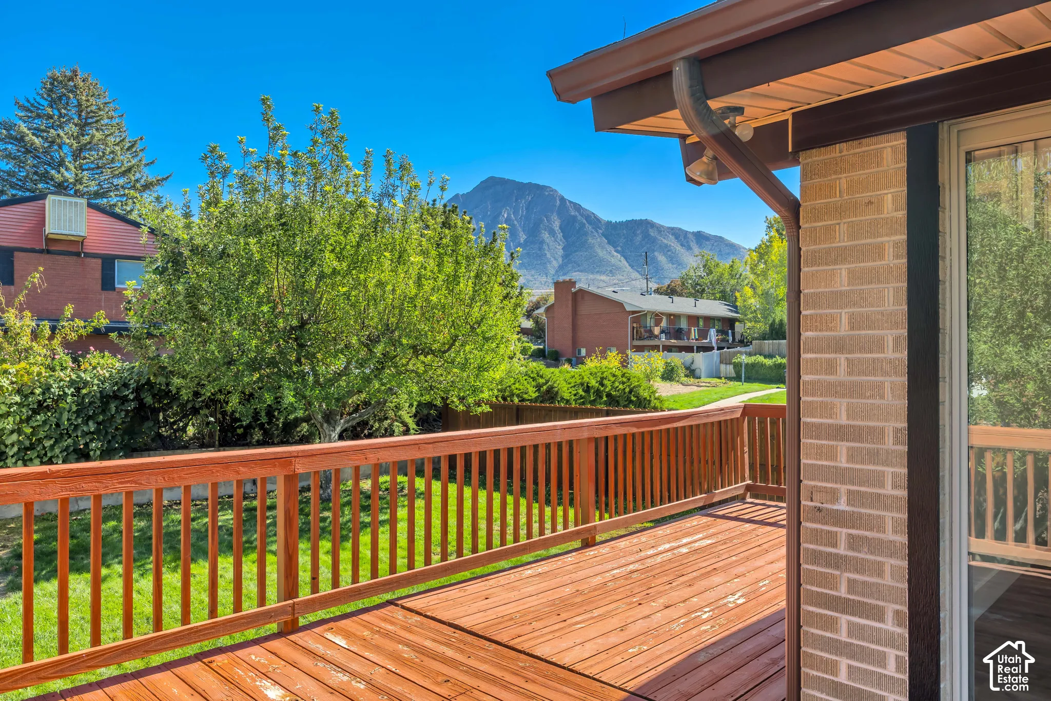 Expansive wood deck with wood railings, brick exterior, and sliding glass door
