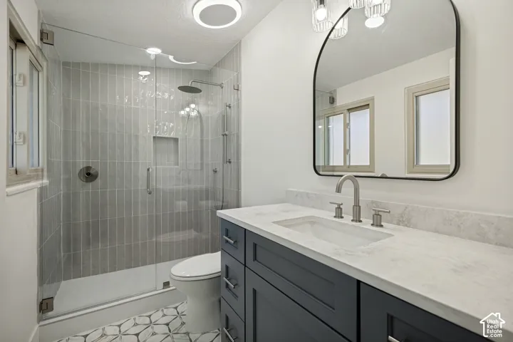 Glass-enclosed shower with vertical tile surround and recessed niche