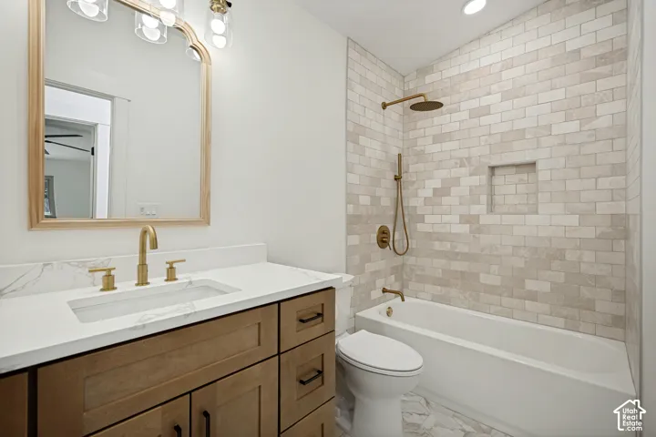Bathroom featuring a wood-finish vanity with a white countertop and gold-tone fixtures