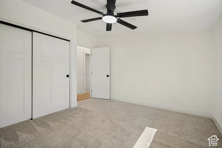 Wall-to-wall carpeting with light-toned walls, white panel doors, and a ceiling fan with integrated lighting