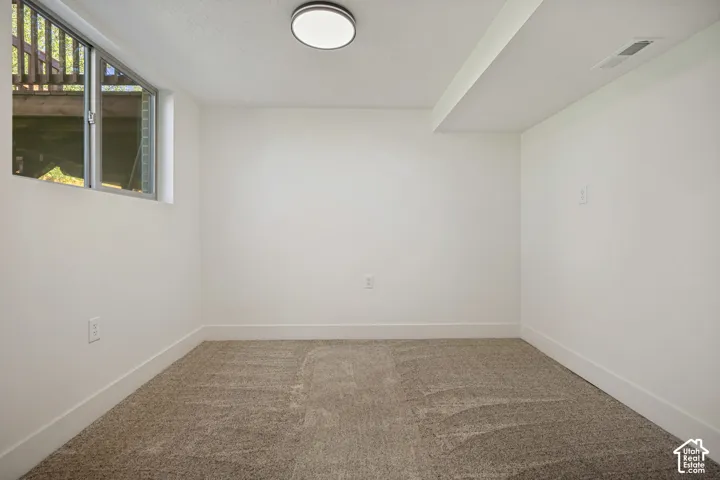 Recessed window, neutral wall paint, flush-mount ceiling light, carpeting, and white baseboards