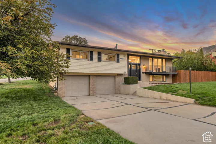 Split-level exterior featuring brick and siding, a dual-door garage, and an upper-level balcony
