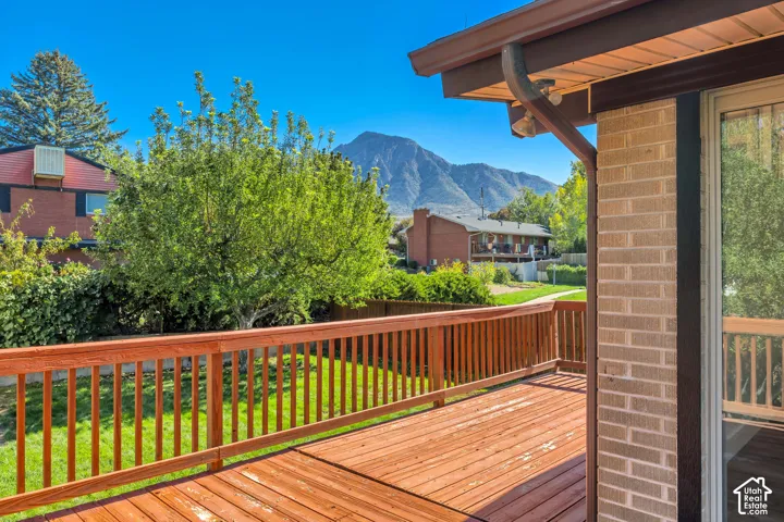 Expansive wood deck with wood railings, brick exterior, and sliding glass door