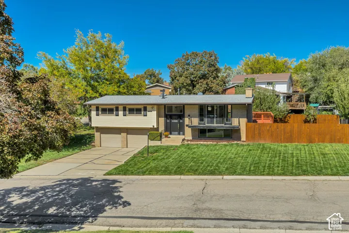 Split-level residence featuring a two-car garage, concrete driveway, and a front lawn with a gentle incline