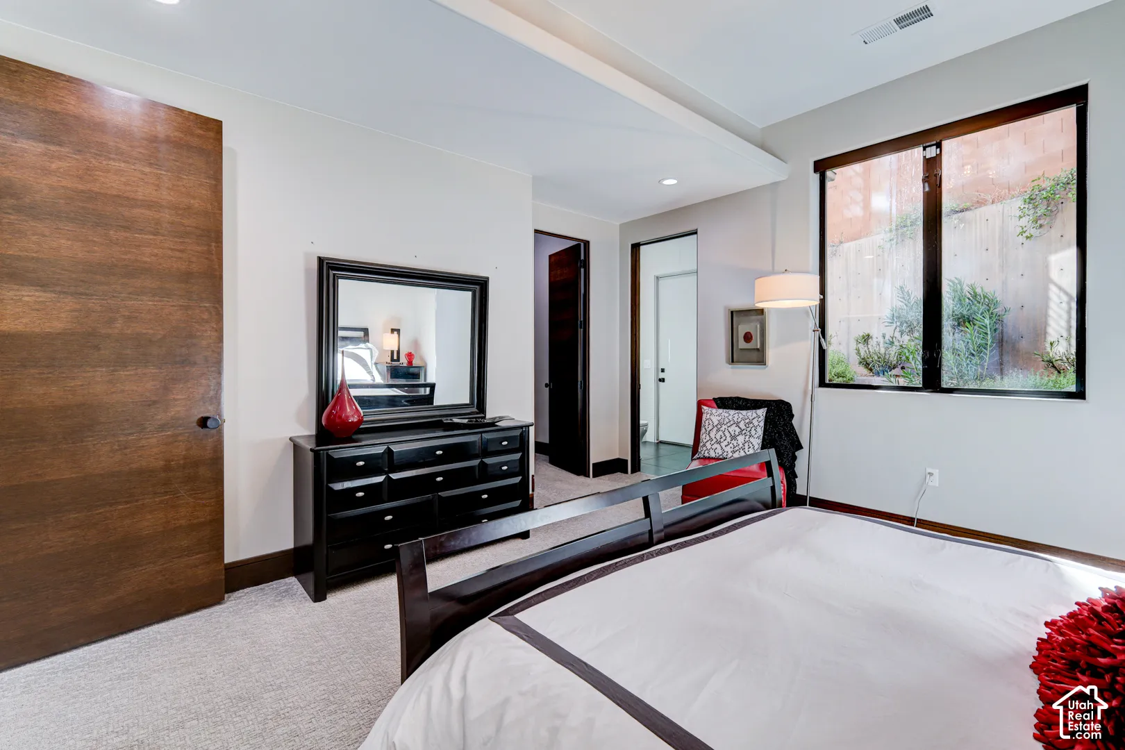 Recessed ceiling lighting, wood-finish interior door, light-toned carpeting, black window trim, and a built-in wall niche