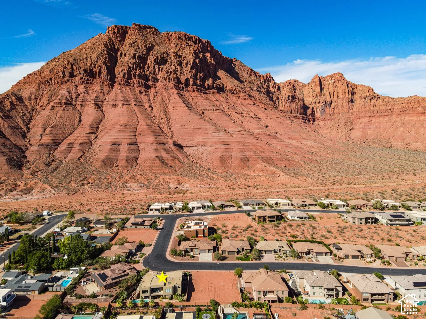 Red rock mountain backdrop with established residential properties and paved roadways
