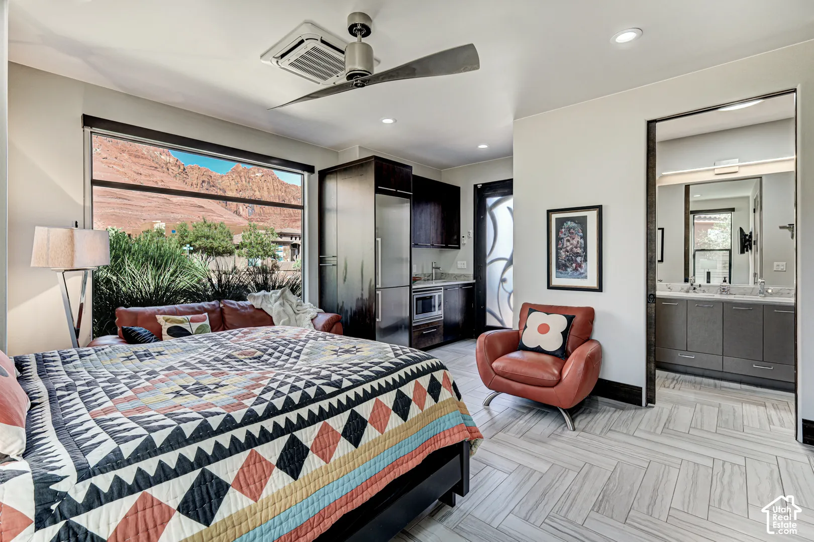 Expansive window with mountain scenery, a recessed ceiling fan, built-in cabinetry, modern flooring, and an adjoining bathroom featuring a dual vanity
