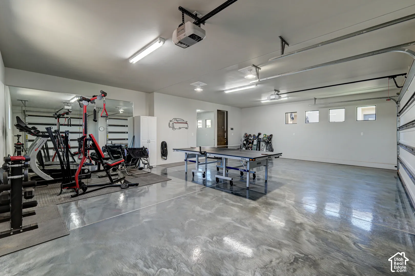 Expansive finished garage space featuring an epoxy floor, white walls, multiple windows, and a segmented garage door