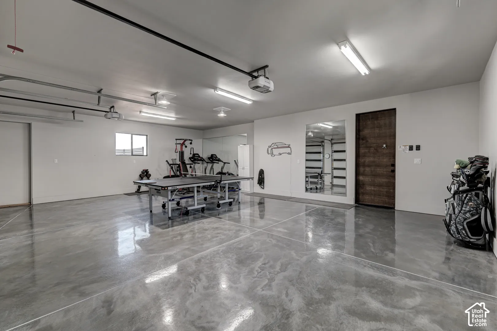 Polished concrete flooring, recessed lighting, track lighting, dark wood-finish door, and a built-in mirror