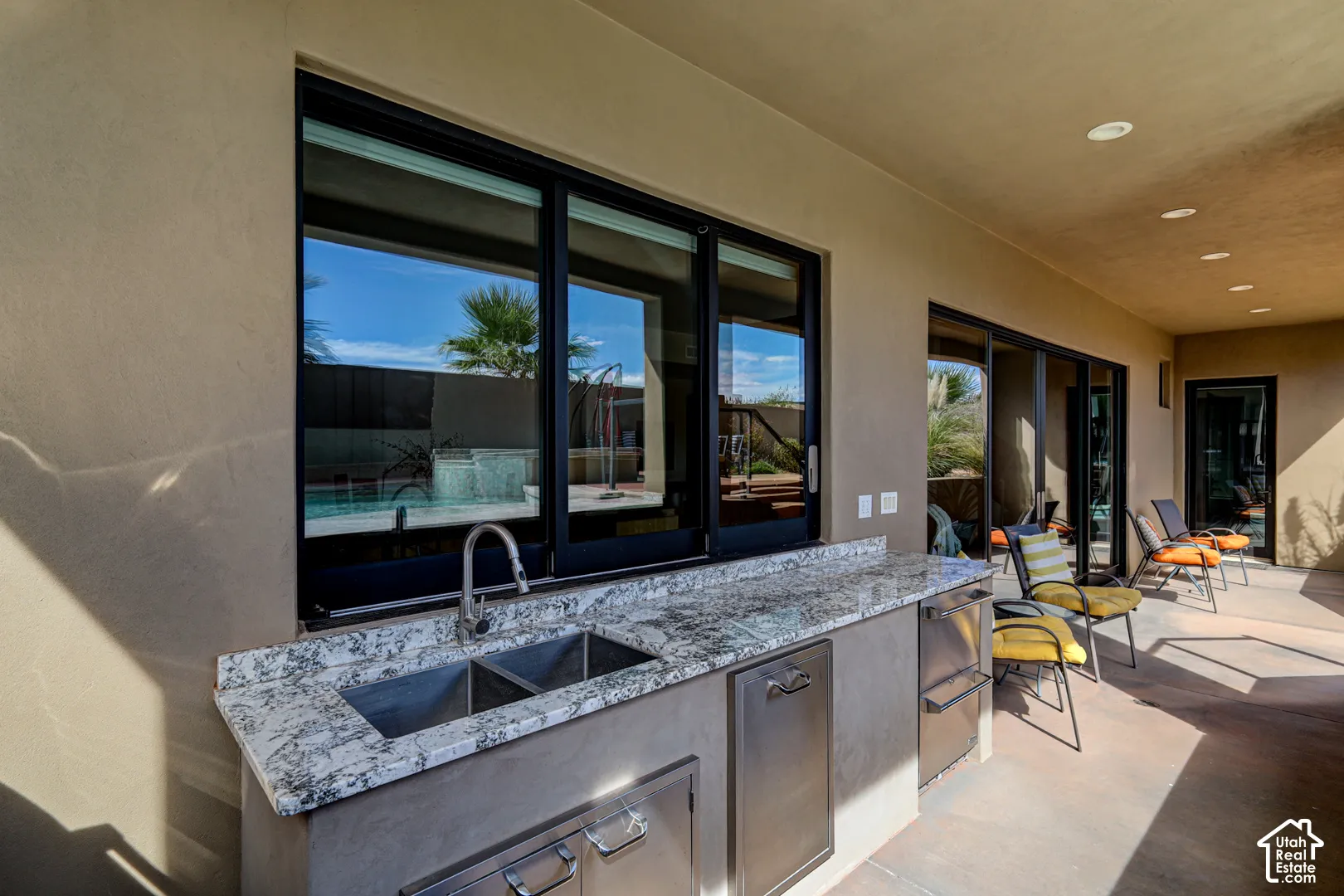 Outdoor kitchen featuring a dual-basin sink, stainless steel appliances, and a polished stone countertop