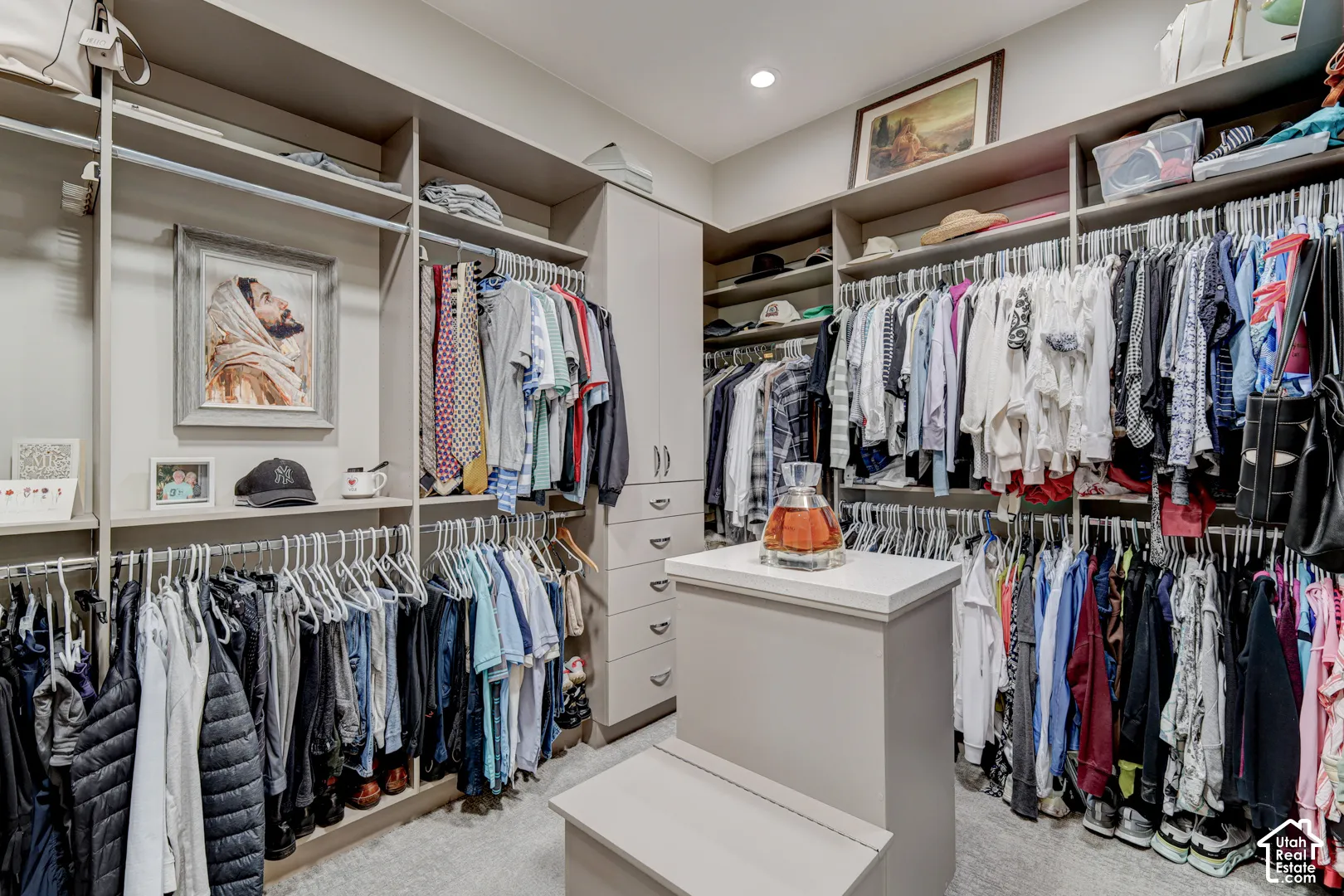 Custom closet system with multiple hanging rods, integrated shelving, built-in drawers, and a central island