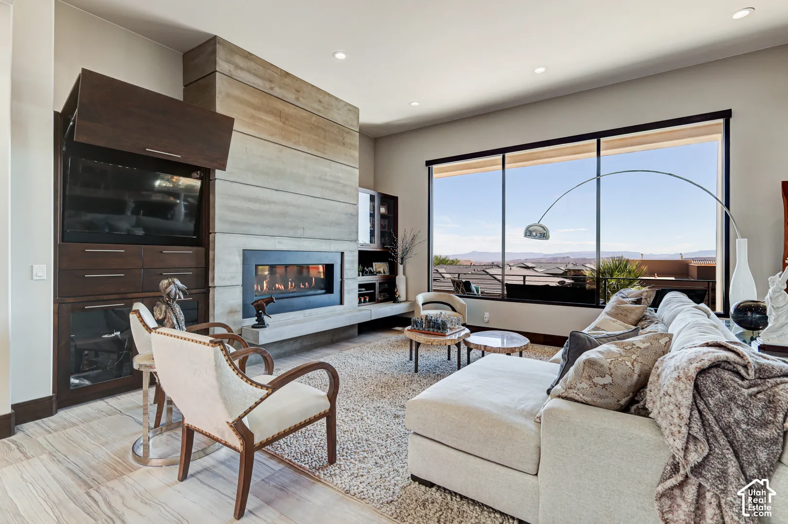Integrated linear fireplace with a concrete surround, dark wood-finish built-in cabinetry, large picture windows, and light wood-look tile flooring