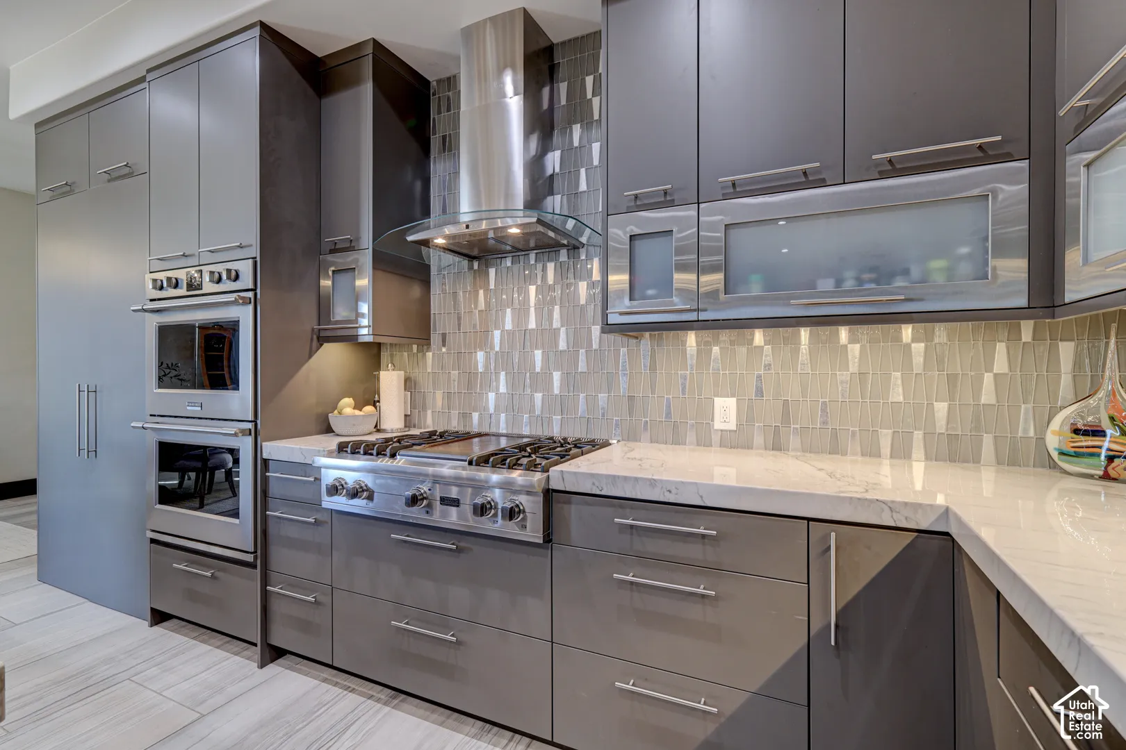 Contemporary kitchen featuring gray cabinetry, stainless steel appliances, a tile backsplash, and light-toned countertops