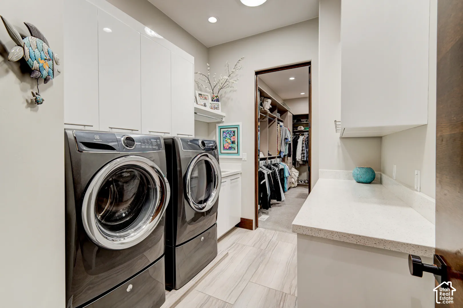 White upper cabinetry, light-toned wood-finish flooring, recessed lighting, and a white countertop