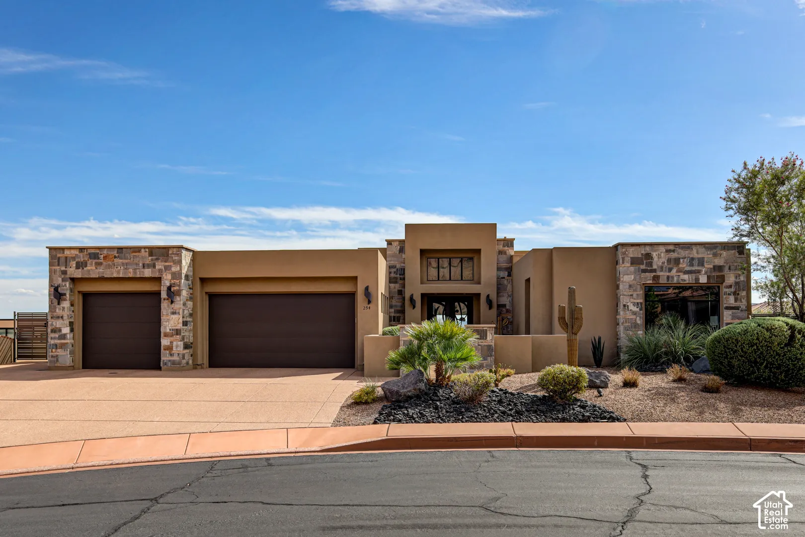 Stucco exterior with stone accents, two-car garage, and desert landscaping
