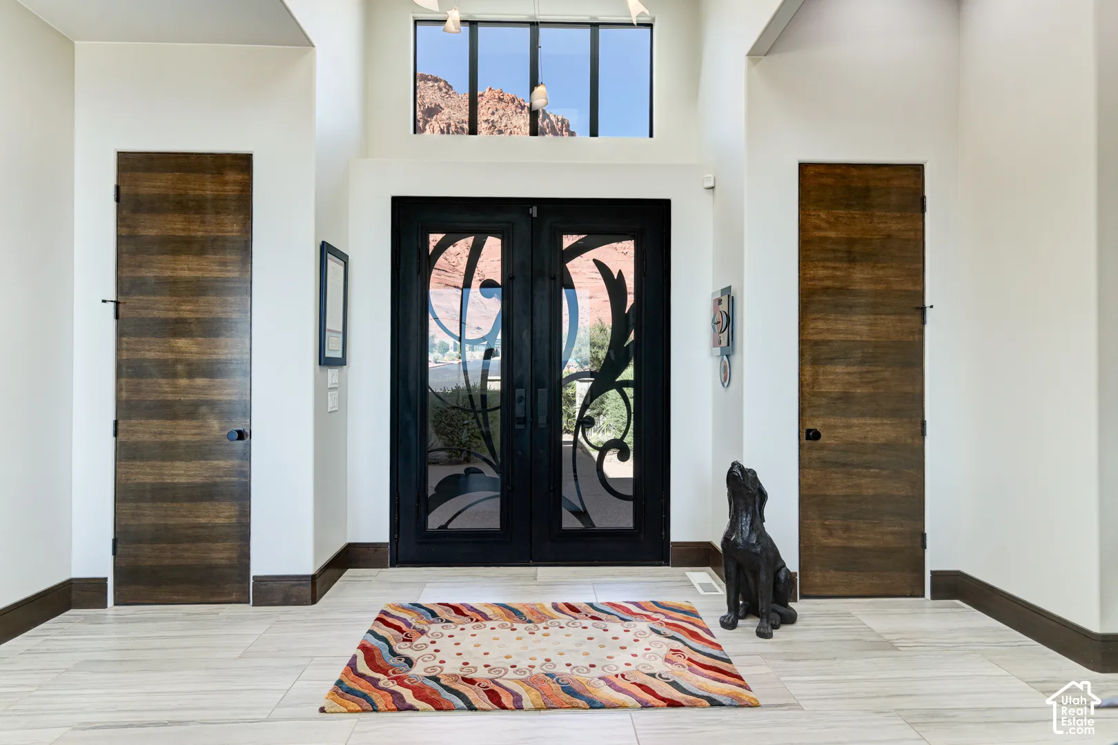 Double entry doors with decorative ironwork, transom window, and vaulted ceiling