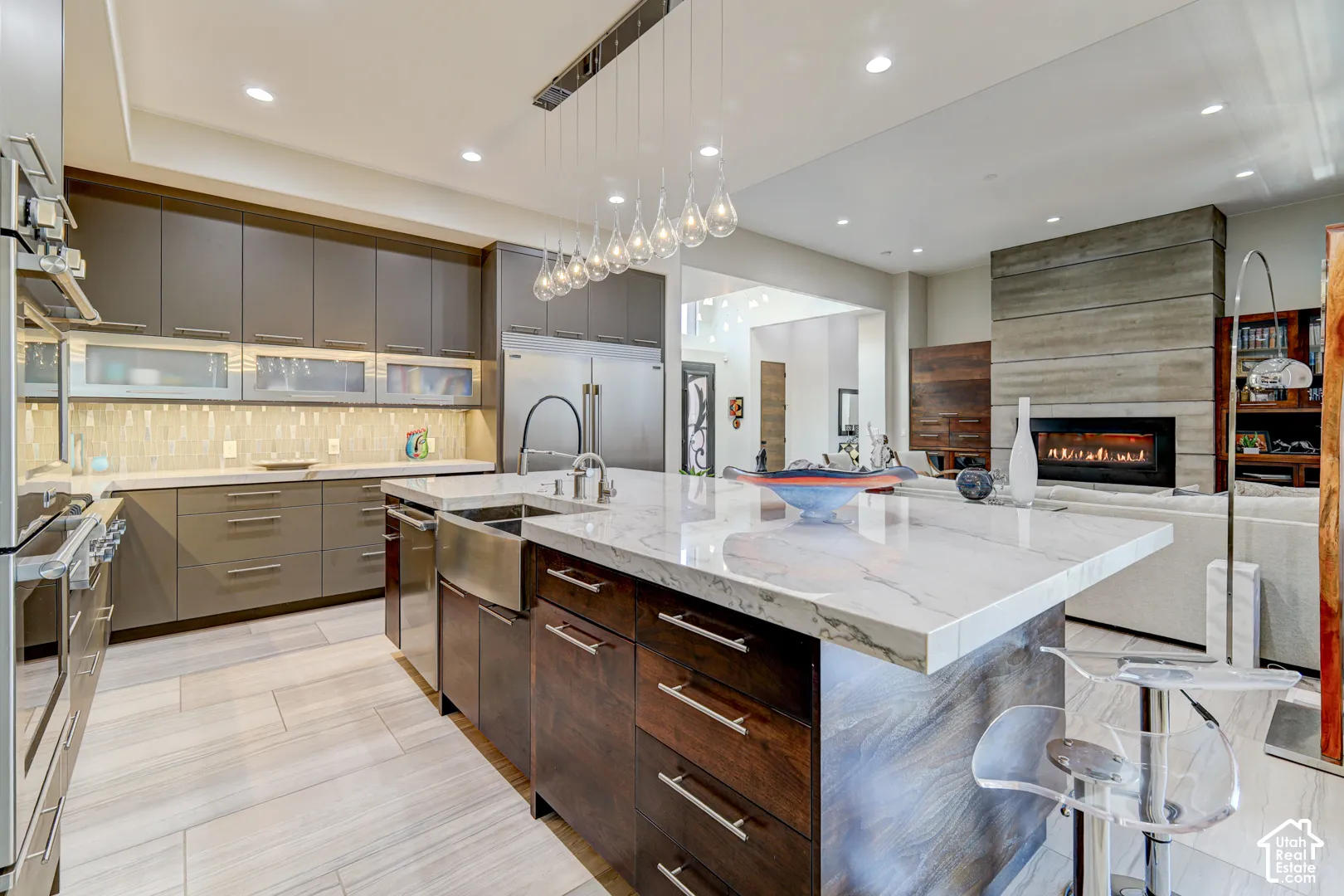Open-concept kitchen with a large central island, stainless steel appliances, and a tiled backsplash