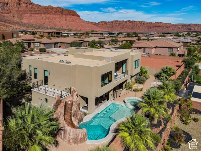 Modern stucco exterior with multiple balconies, a custom-shaped pool, a built-in spa, and a rock-feature slide