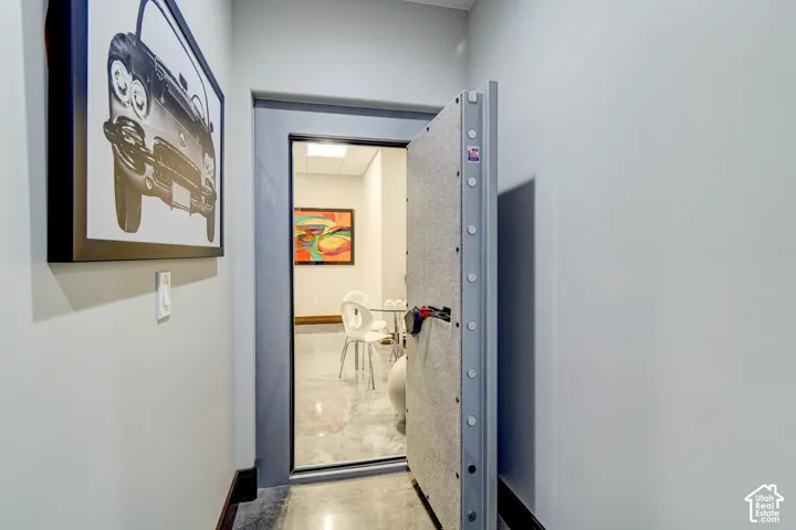 Vault door entry leading to an interior space with polished concrete flooring and recessed lighting