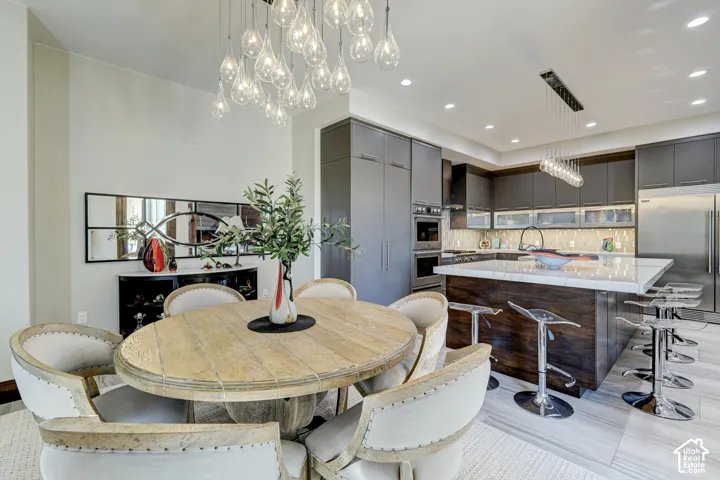Modern kitchen featuring dark cabinetry, stainless steel appliances, and a large central island with seating