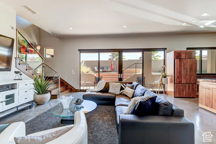 Staircase with wood treads and stainless steel railing, large sliding glass doors, recessed lighting, wood-finish cabinetry, and built-in wood-paneled refrigerator