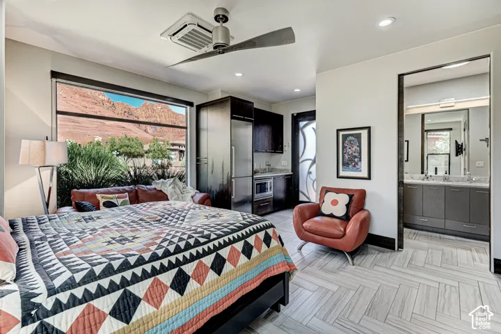 Expansive window with mountain scenery, a recessed ceiling fan, built-in cabinetry, modern flooring, and an adjoining bathroom featuring a dual vanity
