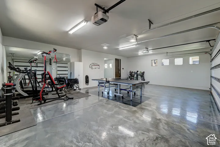 Expansive finished garage space featuring an epoxy floor, white walls, multiple windows, and a segmented garage door